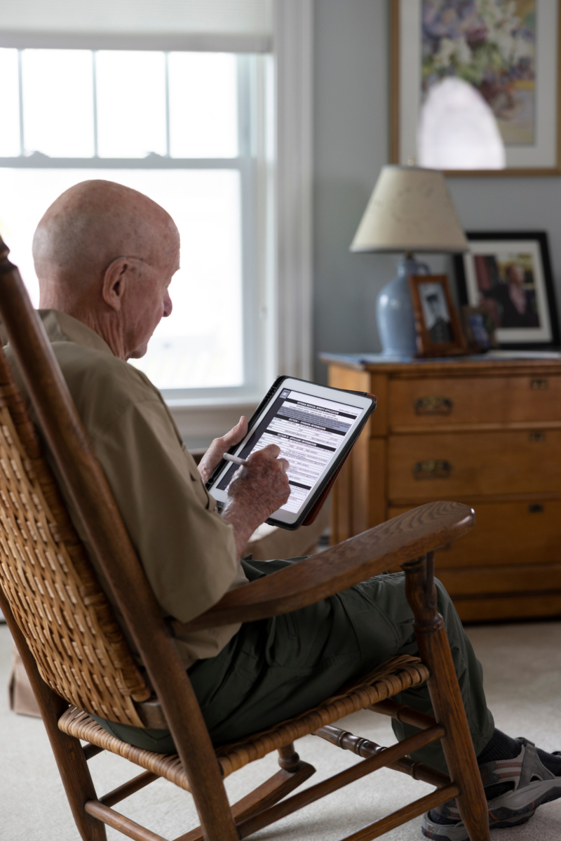 Elderly man using tablet in a rocking chair indoors